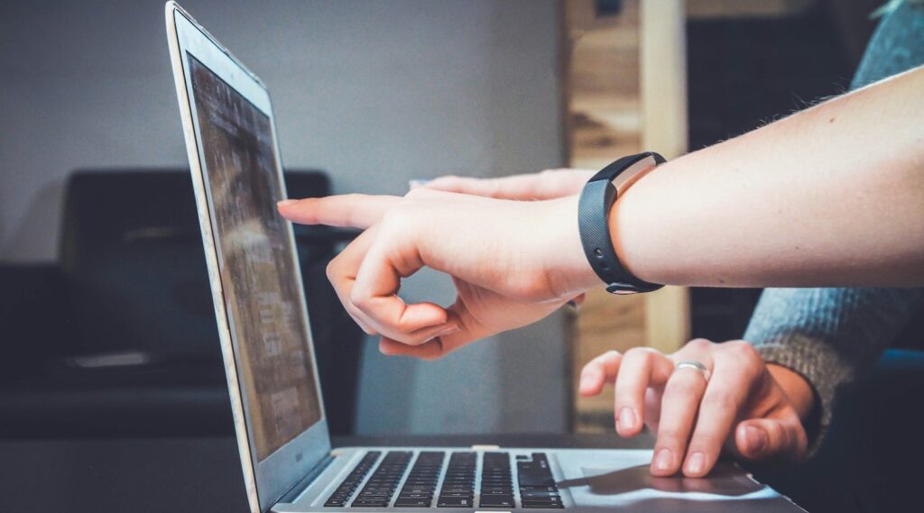 2 people using a laptop pointing at the screen